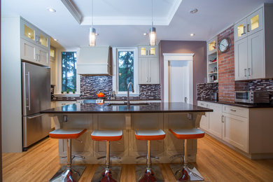 Mid-sized elegant u-shaped medium tone wood floor open concept kitchen photo in Calgary with a double-bowl sink, white cabinets, multicolored backsplash, stainless steel appliances and an island