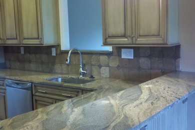 Example of a mid-sized minimalist u-shaped eat-in kitchen design in Atlanta with an undermount sink, raised-panel cabinets, distressed cabinets, granite countertops, beige backsplash, stone tile backsplash and stainless steel appliances