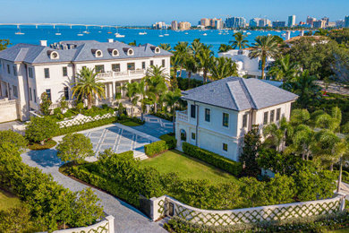 Example of a huge classic white three-story stone house exterior design in Tampa with a tile roof