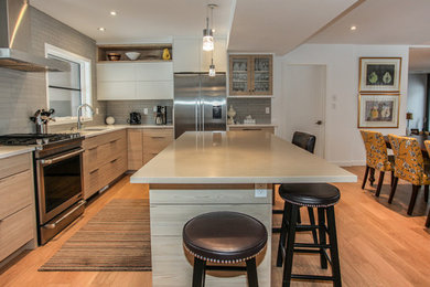 Mid-sized contemporary l-shaped eat-in kitchen in Toronto with an undermount sink, flat-panel cabinets, beige cabinets, quartz benchtops, grey splashback, subway tile splashback, stainless steel appliances, light hardwood floors, with island and brown floor.
