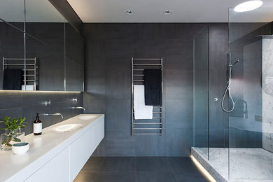 Photo of a large modern master bathroom in New York with flat-panel cabinets, white cabinets, a corner shower, grey walls, an integrated sink, engineered quartz benchtops, porcelain floors and grey floor.