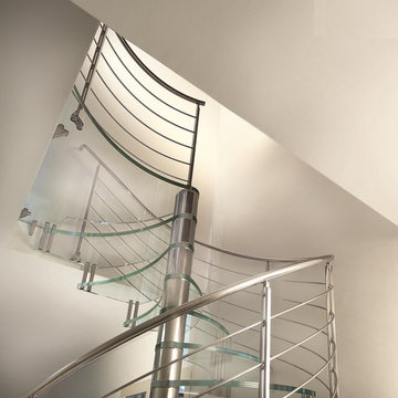 Escalier à colimaçon en inox et marches en verre et garde-corps en inox