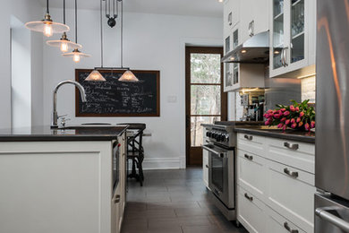Mid-sized country single-wall porcelain tile enclosed kitchen photo in Montreal with an undermount sink, shaker cabinets, white cabinets, quartz countertops, white backsplash, brick backsplash, stainless steel appliances and an island