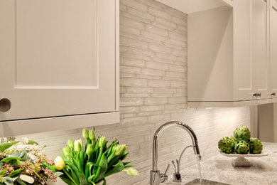 Inspiration for a transitional l-shaped medium tone wood floor open concept kitchen remodel in Seattle with an undermount sink, recessed-panel cabinets, white cabinets, metallic backsplash, porcelain backsplash, stainless steel appliances and an island