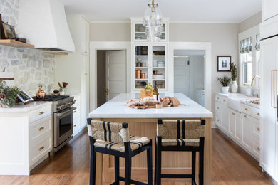 Inspiration for a large timeless medium tone wood floor and brown floor open concept kitchen remodel in Los Angeles with a farmhouse sink, shaker cabinets, white cabinets, quartz countertops, multicolored backsplash, stone slab backsplash, paneled appliances, an island and white countertops