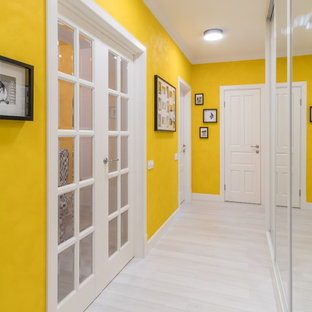 Foto på en vintage hall, med gula väggar, vitt golv och målat trägolv