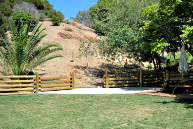 This is an example of an expansive country sloped partial sun garden in Los Angeles with natural stone pavers.
