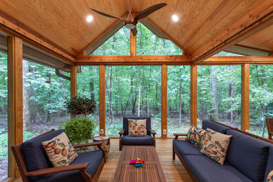 This is an example of a large rustic screened-in back porch design in Raleigh with decking and a roof extension.