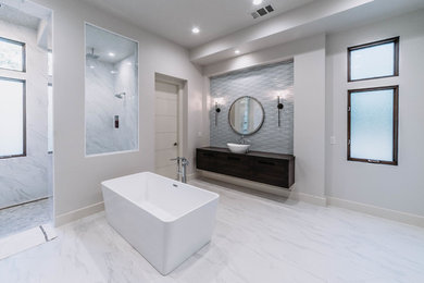 Photo of an expansive contemporary master bathroom in Sacramento with flat-panel cabinets, dark wood cabinets, a freestanding tub, an alcove shower, gray tile, white walls, marble floors, a vessel sink, wood benchtops, white floor, an open shower and brown benchtops.