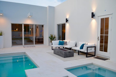 Example of a mid-sized classic backyard stamped concrete and custom-shaped hot tub design in Miami