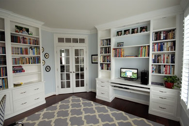 Large transitional built-in desk medium tone wood floor and brown floor study room photo in DC Metro with blue walls