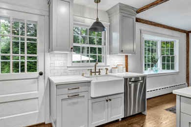 Inspiration for a large cottage u-shaped medium tone wood floor, brown floor and exposed beam eat-in kitchen remodel in New York with a farmhouse sink, shaker cabinets, gray cabinets, quartz countertops, white backsplash, subway tile backsplash, stainless steel appliances, an island and white countertops