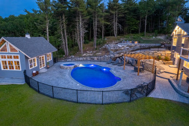 Modelo de piscina natural actual grande a medida en patio trasero con paisajismo de piscina y adoquines de hormigón
