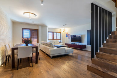 Living room - contemporary medium tone wood floor, brown floor, tray ceiling and brick wall living room idea with beige walls