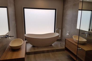 Photo of a mid-sized modern master bathroom in Other with a freestanding tub, brown tile, cement tile, ceramic floors, laminate benchtops and brown floor.