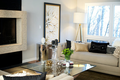 Photo of a mid-sized contemporary formal open concept living room in Edmonton with white walls, medium hardwood floors, a standard fireplace, a concrete fireplace surround and no tv.