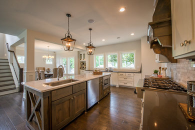 Example of a transitional single-wall dark wood floor open concept kitchen design in Minneapolis with a single-bowl sink, shaker cabinets, white cabinets, quartzite countertops, white backsplash, marble backsplash, stainless steel appliances and an island