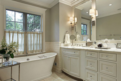 Mid-sized traditional master bathroom in New Orleans with recessed-panel cabinets, white cabinets, a freestanding tub, white tile, subway tile, grey walls, travertine floors, an undermount sink, marble benchtops and beige floor.