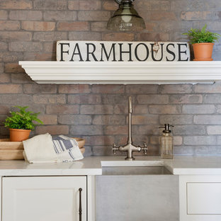 Bild på ett stort lantligt vit vitt kök, med en rustik diskho, vita skåp, flerfärgad stänkskydd, stänkskydd i tegel, rostfria vitvaror och en köksö