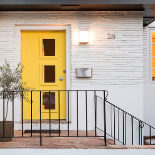 チャールストンの片開きドアミッドセンチュリースタイルのおしゃれな玄関ドア (白い壁、スレートの床、黄色いドア) の写真
