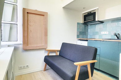 Réalisation d'un petit salon design avec un mur blanc, parquet clair et poutres apparentes.