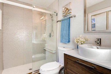 Example of a mid-sized transitional 3/4 ceramic tile and beige tile bathroom design in Other with white cabinets, white walls, shaker cabinets, a two-piece toilet, a vessel sink and quartz countertops