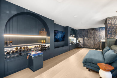 Example of a large minimalist open concept light wood floor, beige floor and wallpaper living room design in San Francisco with a bar, blue walls, a standard fireplace, a plaster fireplace and a wall-mounted tv