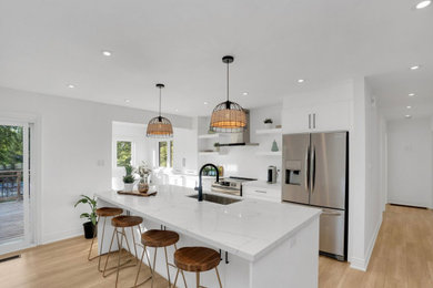 Inspiration for a mid-sized contemporary galley light wood floor and brown floor eat-in kitchen remodel in Philadelphia with an undermount sink, flat-panel cabinets, white cabinets, quartzite countertops, white backsplash, stone slab backsplash, stainless steel appliances, an island and white countertops