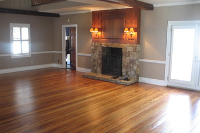 This is an example of a large country formal enclosed living room in Other with beige walls, medium hardwood floors, a standard fireplace, a stone fireplace surround and no tv.