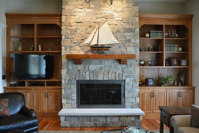 Family room - mid-sized traditional open concept medium tone wood floor family room idea in Orange County with a standard fireplace, a stone fireplace, a media wall and beige walls