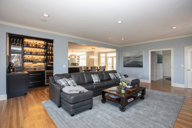 Living room - large modern enclosed medium tone wood floor and brown floor living room idea in Boston with a bar, gray walls, a standard fireplace, a stacked stone fireplace and a wall-mounted tv