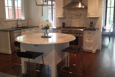 Large trendy galley dark wood floor kitchen photo in Raleigh with a single-bowl sink, beaded inset cabinets, white cabinets, solid surface countertops, gray backsplash, mosaic tile backsplash, stainless steel appliances and an island
