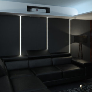 Photo of a large modern open plan home cinema in London with grey walls, slate flooring and a projector screen.
