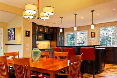 Eat-in kitchen - mid-sized contemporary u-shaped medium tone wood floor eat-in kitchen idea in Seattle with an undermount sink, flat-panel cabinets, brown cabinets, granite countertops, beige backsplash, mosaic tile backsplash, stainless steel appliances and an island
