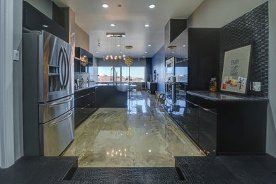 Large trendy l-shaped concrete floor and beige floor eat-in kitchen photo in Calgary with an undermount sink, flat-panel cabinets, black cabinets, quartz countertops, black backsplash, glass tile backsplash, stainless steel appliances and a peninsula