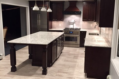 Mid-sized trendy l-shaped porcelain tile and beige floor enclosed kitchen photo in New York with a single-bowl sink, shaker cabinets, dark wood cabinets, stainless steel appliances, an island, granite countertops and gray countertops