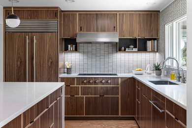 Eat-in kitchen - 1950s l-shaped medium tone wood floor eat-in kitchen idea in Detroit with white backsplash, an island, white countertops, a single-bowl sink, flat-panel cabinets, dark wood cabinets, quartz countertops, mosaic tile backsplash and paneled appliances