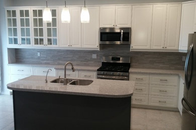 Eat-in kitchen - mid-sized traditional l-shaped porcelain tile eat-in kitchen idea in Toronto with an undermount sink, raised-panel cabinets, white cabinets, quartz countertops, gray backsplash, porcelain backsplash, stainless steel appliances and an island