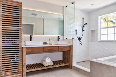 Example of a mid-sized beach style master white tile and ceramic tile beige floor bathroom design in Miami with medium tone wood cabinets, a two-piece toilet, white walls, a vessel sink, quartz countertops and flat-panel cabinets