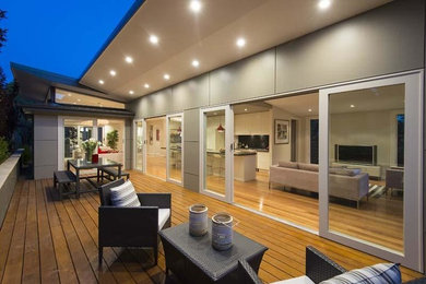 This is an example of a mid-sized contemporary backyard deck in Sydney with a roof extension.