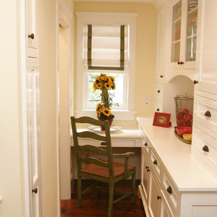 Bild på ett litet maritimt arbetsrum, med gula väggar, mörkt trägolv och ett inbyggt skrivbord