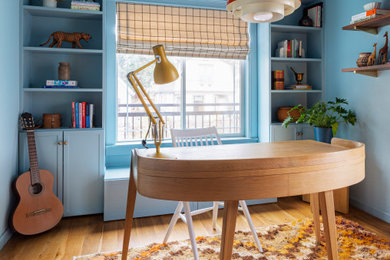 Small eclectic freestanding desk light wood floor home office library photo in Portland with blue walls