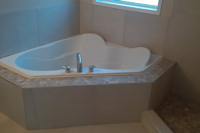 This is an example of a traditional bathroom in Edmonton with a drop-in tub, a corner shower, beige walls and ceramic floors.
