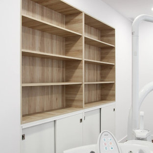 Medium sized modern home office and library in Palma de Mallorca with white walls, laminate floors and brown floors.