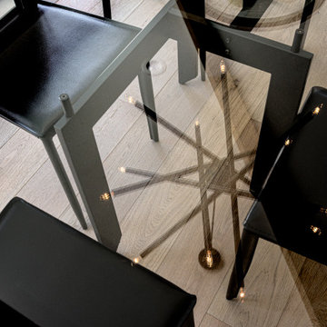 Reflection of Black Dining Chandelier over Glass Top Dining Table and Hardwood F