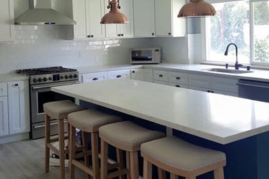 Inspiration for a modern u-shaped porcelain tile eat-in kitchen remodel in Los Angeles with a single-bowl sink, recessed-panel cabinets, white cabinets, quartz countertops, white backsplash, subway tile backsplash, stainless steel appliances and an island