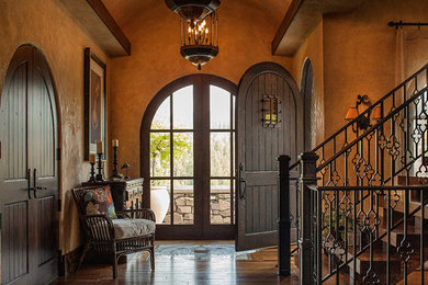 Entryway - large mediterranean medium tone wood floor and brown floor entryway idea in Other with a dark wood front door and beige walls