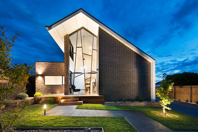 Photo of a mid-sized contemporary two-storey brick black exterior in Melbourne with a gable roof.