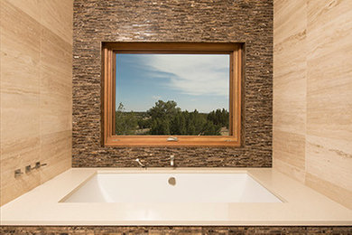 Photo of a contemporary master bathroom in Albuquerque with a drop-in tub, beige tile and beige walls.