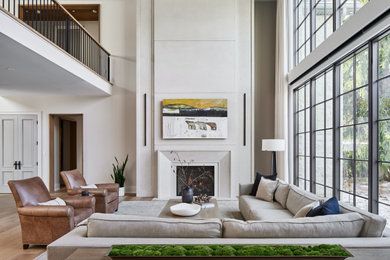 Exempel på ett mycket stort modernt allrum med öppen planlösning, med vita väggar, ljust trägolv, en standard öppen spis och en dold TV